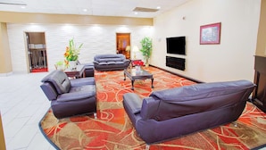 A spacious living area with leather sofas, a flat-screen TV, and a red patterned carpet.