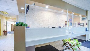 A reception area with a stone wall, a counter, and a clock displaying 12:29.