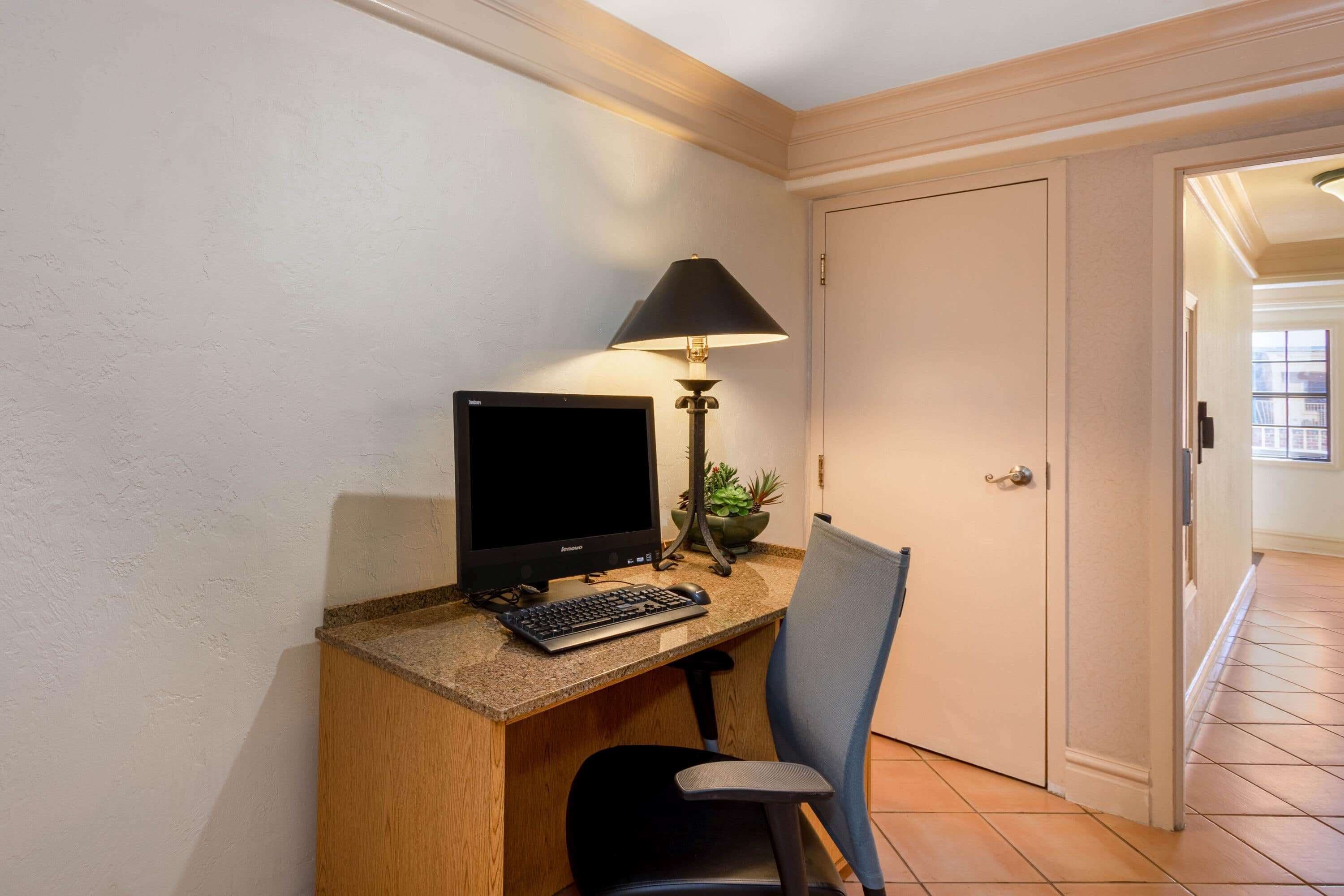 A home office with a computer, keyboard, and chair.