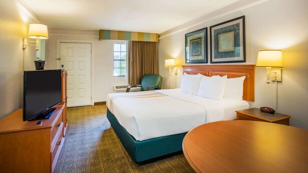 A hotel room with a bed, a TV, a desk, and a chair.