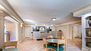 A spacious dining area with a round table and chairs, a kitchen area with a counter and appliances, and a tiled floor.