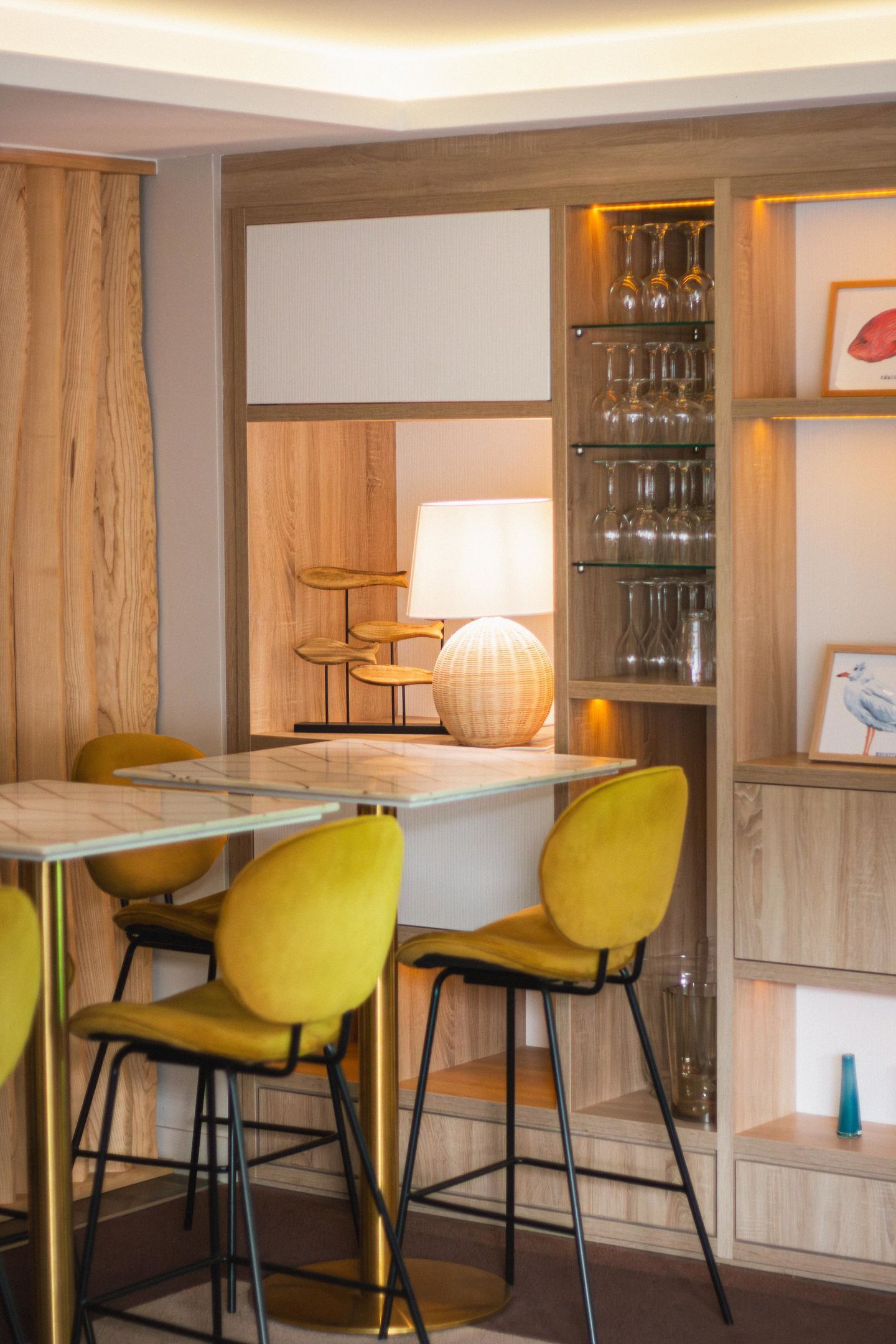 A dining area with a table, chairs, and a shelf with glasses.