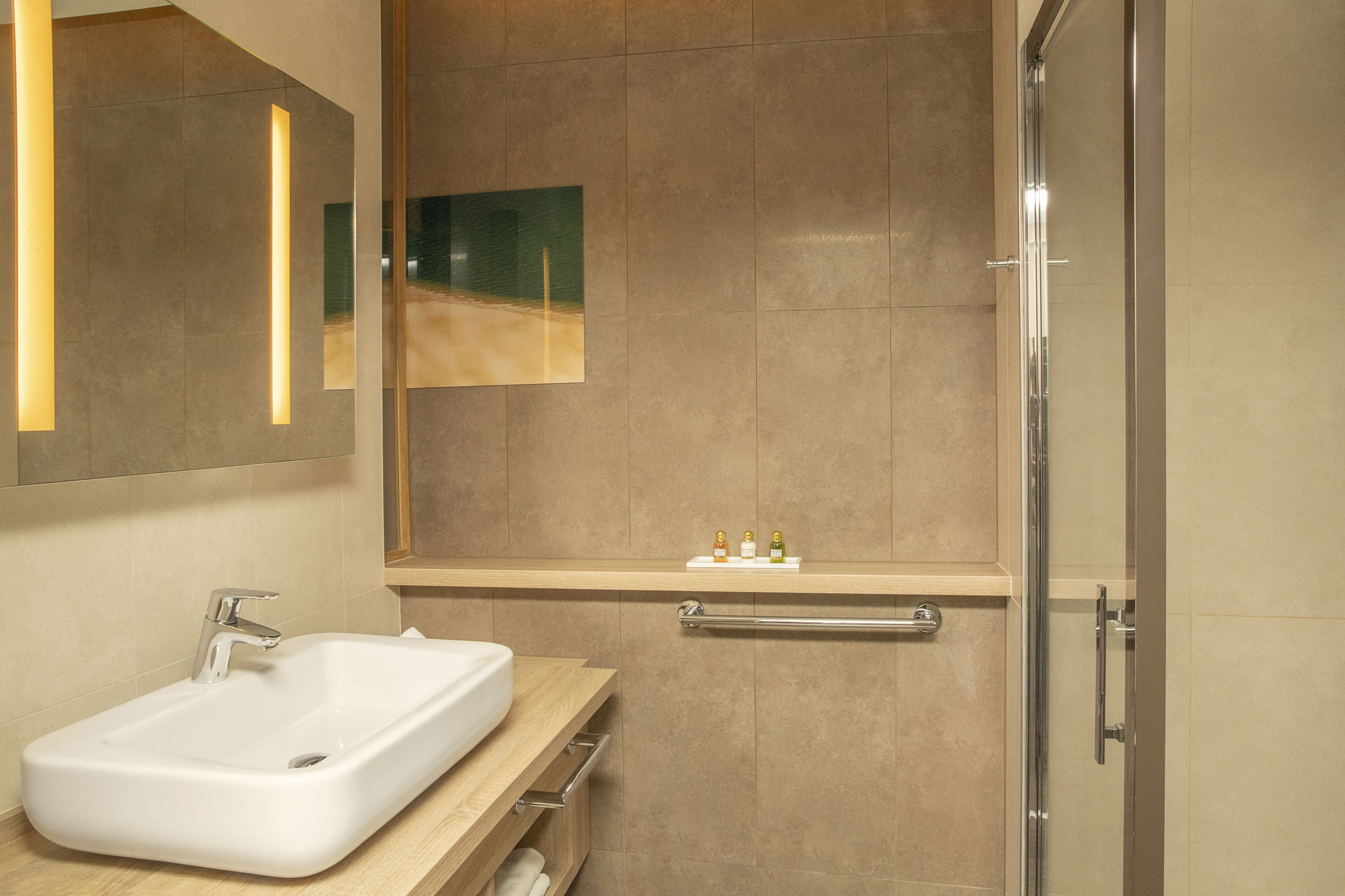 Un baño moderno con un lavamanos rectangular, un espejo y una puerta de ducha de vidrio.