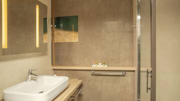 Un baño moderno con un lavamanos rectangular, un espejo y una puerta de ducha de vidrio.