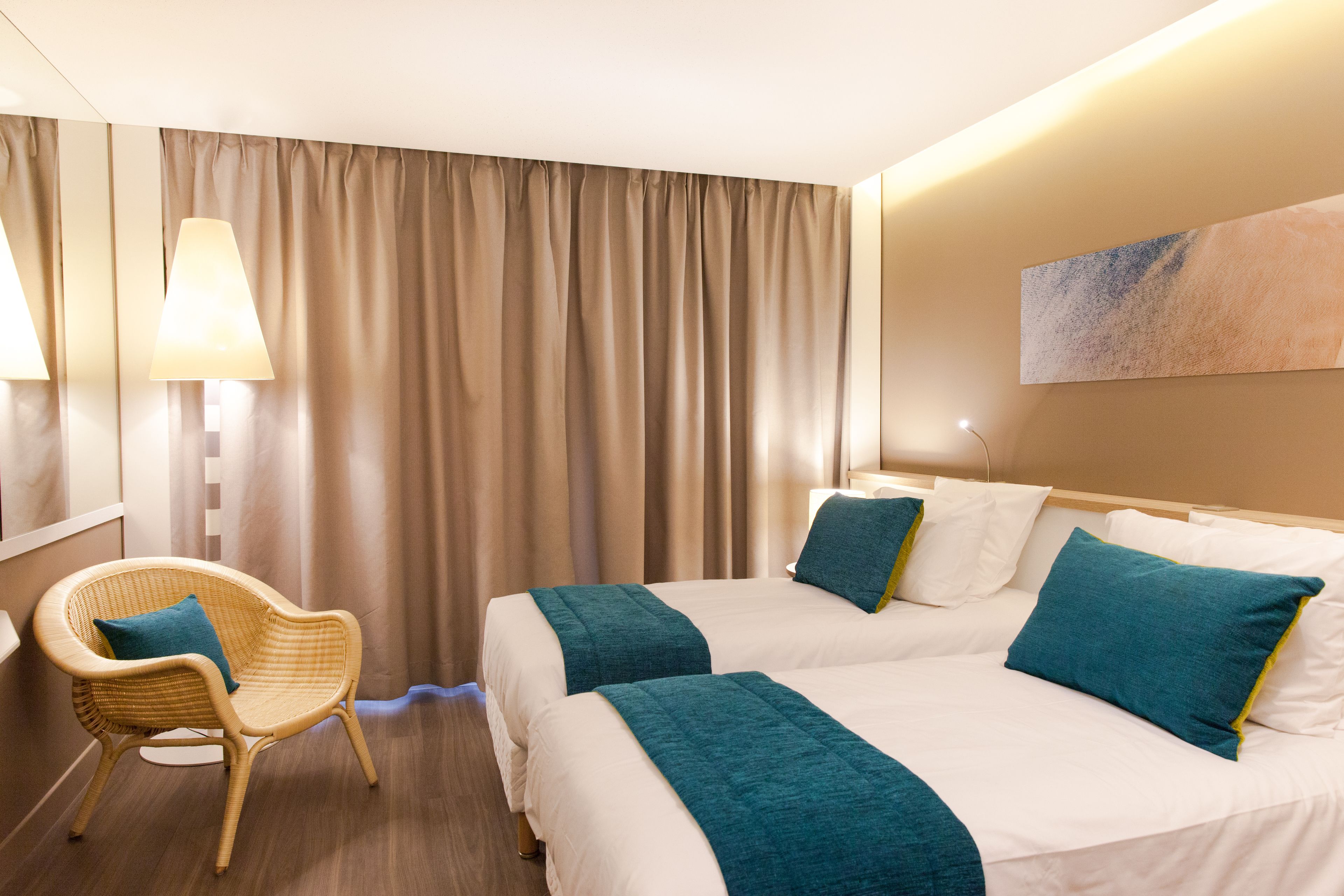 Une chambre d’hôtel avec deux lits, une chaise et un tableau au mur.