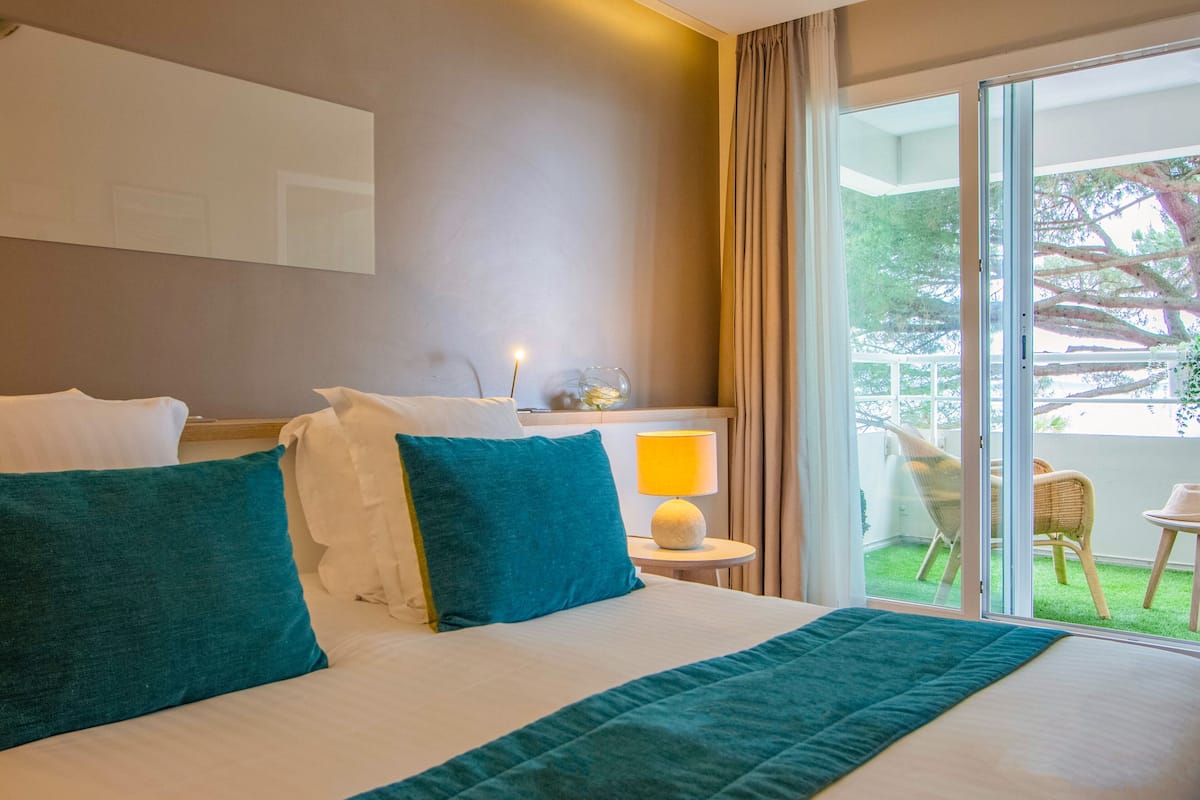 Une chambre d’hôtel avec un grand lit, une table de chevet avec une lampe et une vue sur l’extérieur grâce à une porte coulissante.