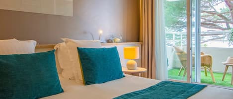 Une chambre d’hôtel avec un grand lit, une table de chevet avec une lampe et une vue sur l’extérieur grâce à une porte coulissante.