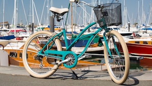 A teal bicycle with a basket, parked by a marina with boats in the background. - Hôtel Le B d’Arcachon by Inwood Hotels (Arcachon)