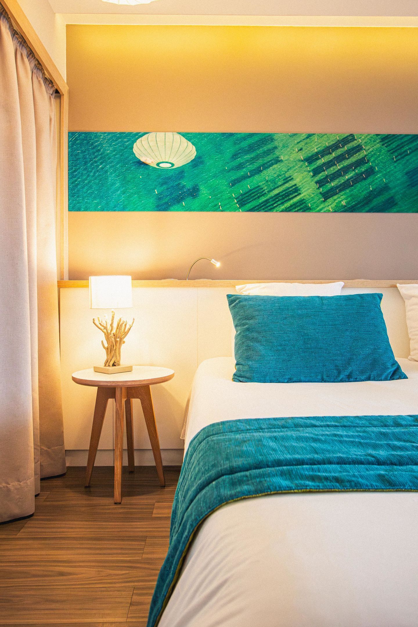 A hotel room with a bed, a nightstand, a lamp, and a wall art piece.