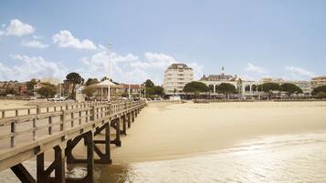 A pier extending into a calm beach with a clear sky.