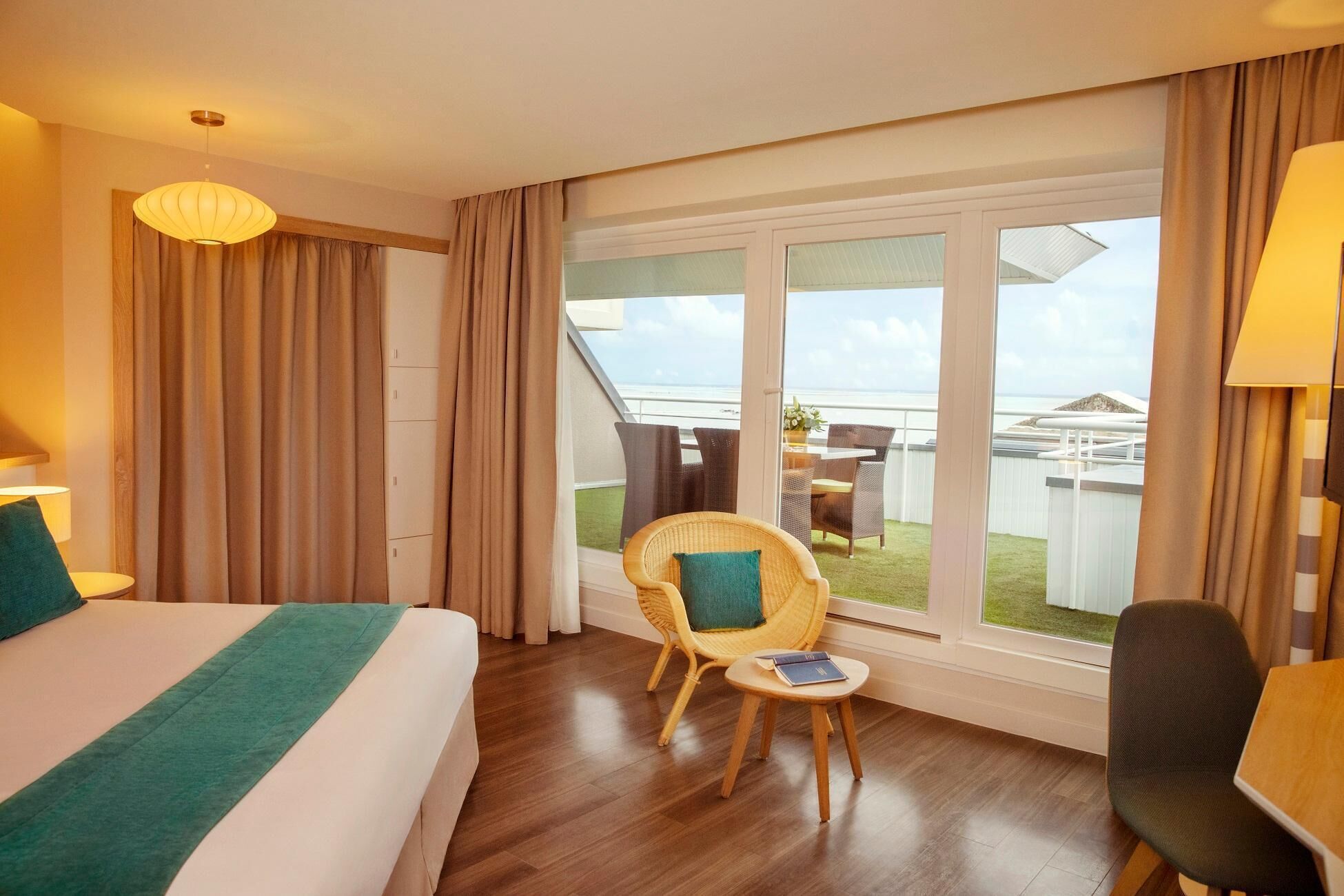 Une chambre d’hôtel avec un lit, une chaise, une petite table et un balcon avec vue.