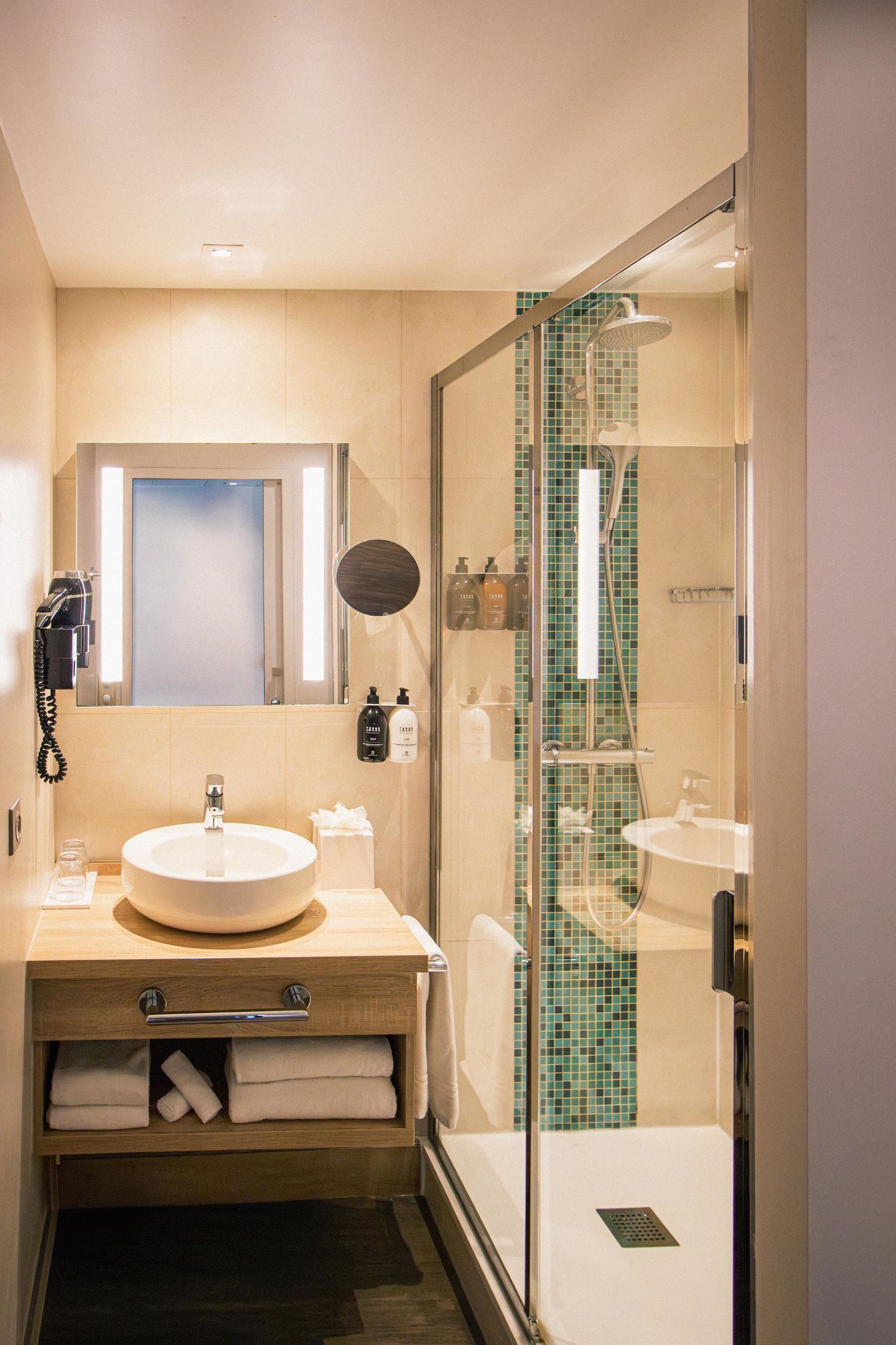 A modern bathroom with a sink, mirror, and shower area.