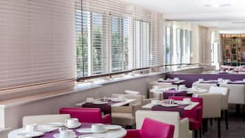 A restaurant with round tables and chairs, some with purple tablecloths.