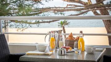 Enjoy a beachside breakfast on your balcony with a view of the ocean and a palm tree.