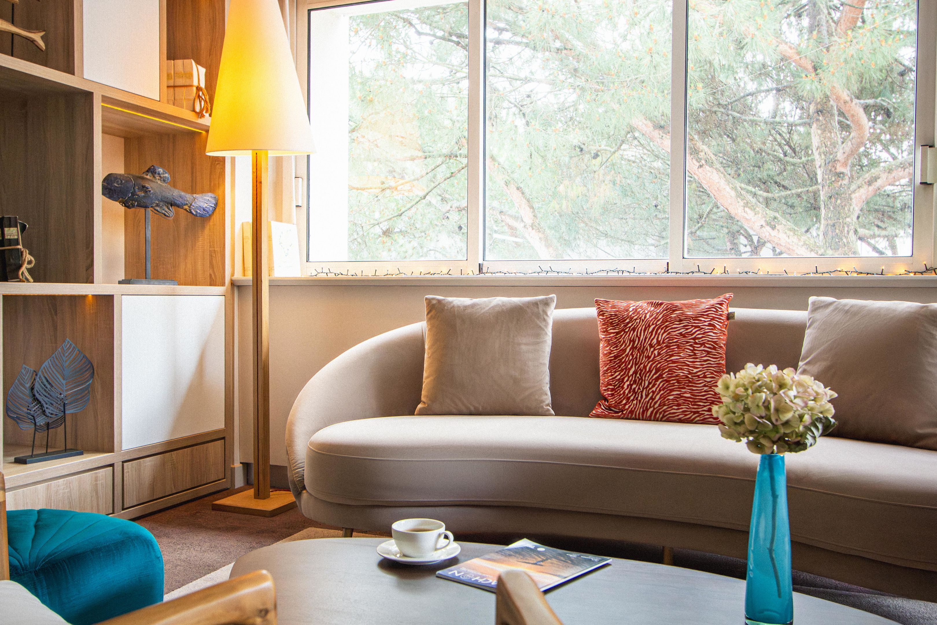 Una habitación acogedora con un sofá, una mesita de centro, una lámpara y una ventana con vistas a árboles.
