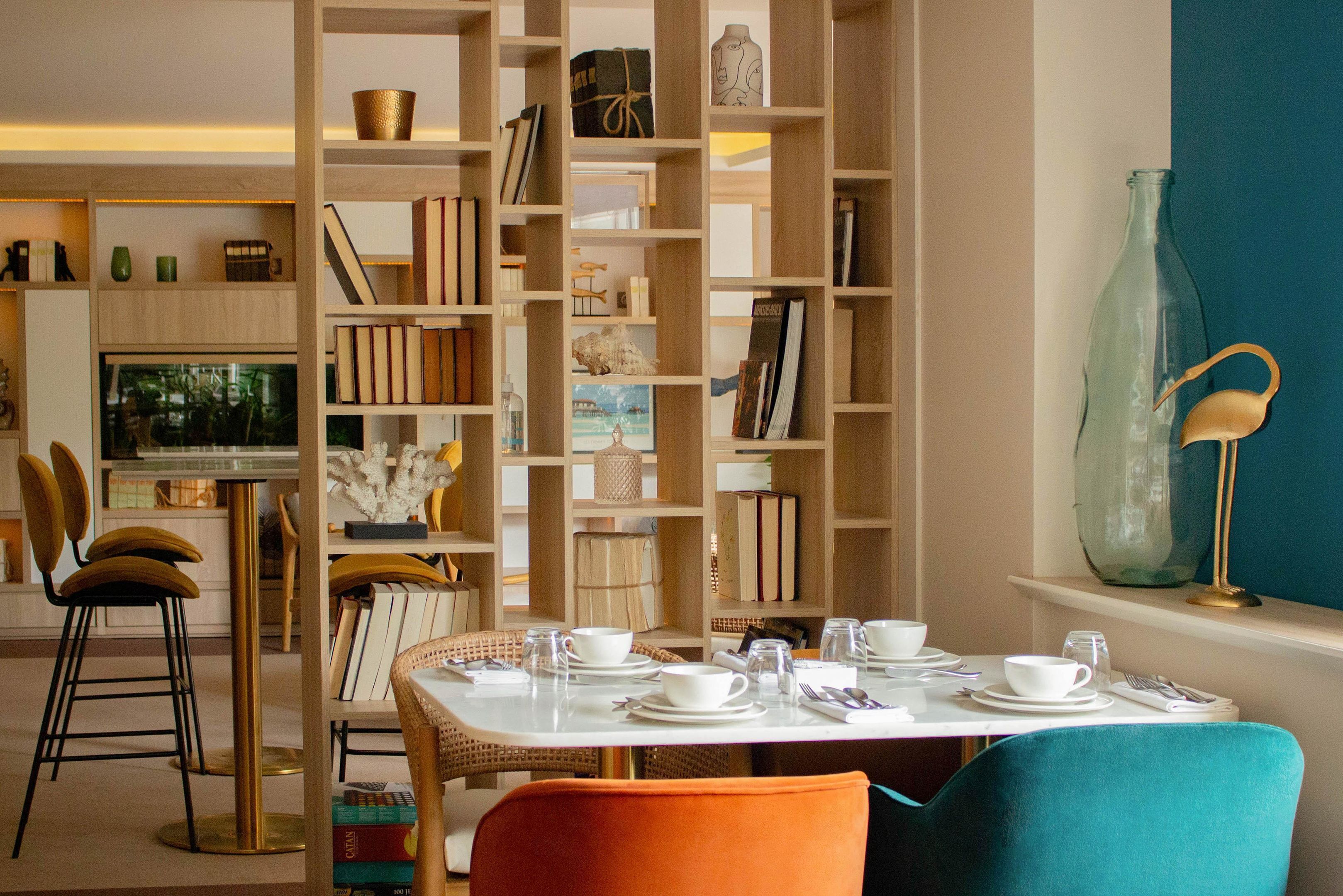 A dining area with a table set for two, surrounded by a bookshelf filled with books and decorative items.