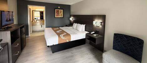 Ein Hotelzimmer mit Bett, Nachttisch, Fernseher und einer Sitzecke.
