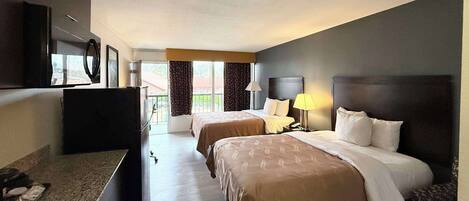 A hotel room with two beds, a desk, a TV, and a window with curtains.