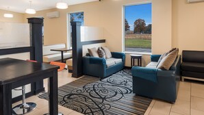 A modern lounge area with a black and white patterned rug, blue sofas, and a black table with a bar stool. - Jasper Inn (Jasper)