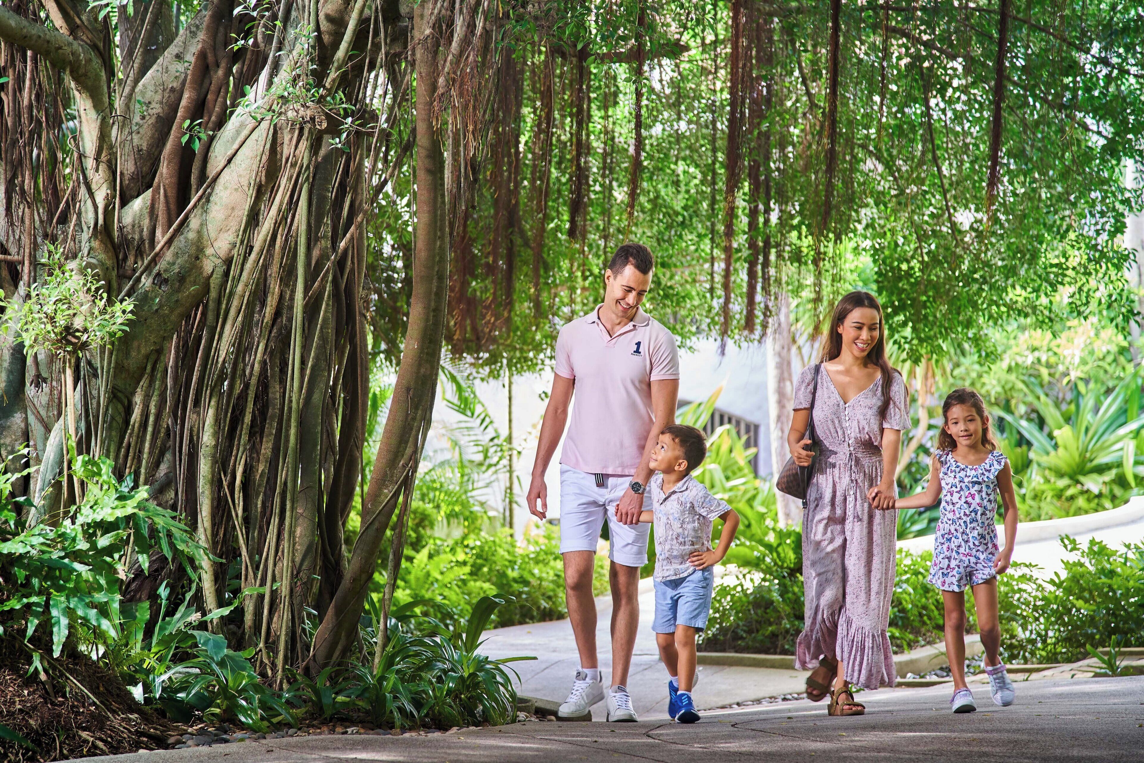 Una família passeja per un camí envoltat de verdura i arbres.