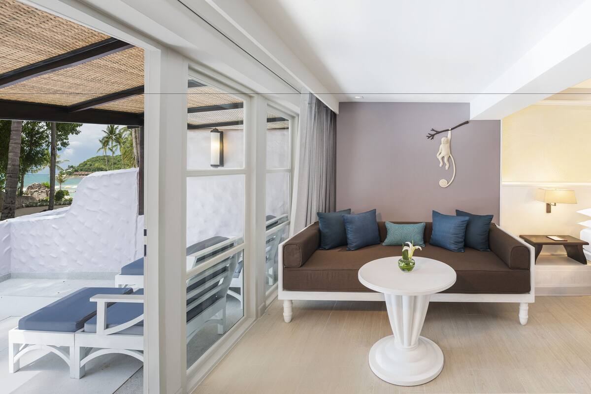 A modern hotel room with a sofa, a small round table, and a bed.