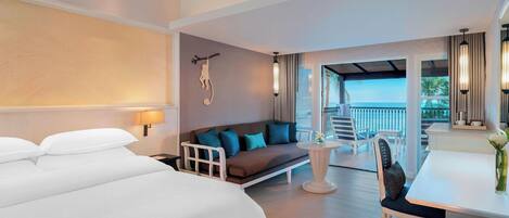 A hotel room with a large bed, a sofa, a dining table, and a balcony with a view.