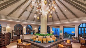 A spacious lobby with a high ceiling, a central seating area with cushions, and a bar with shelves of bottles. - Sheraton Samui Resort (Koh Samui)
