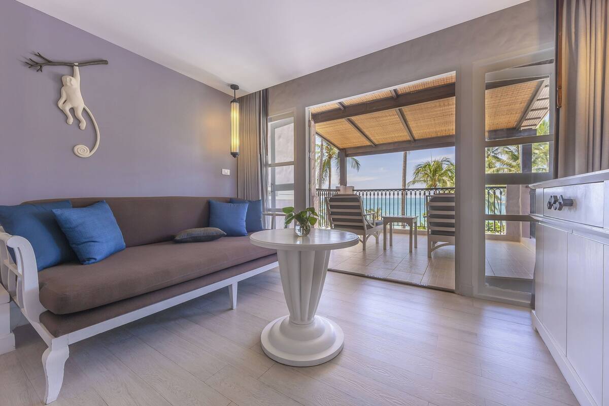 A modern living room with a sofa, a round table, and a view of an outdoor pool area.