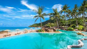 A resort pool with clear blue water, surrounded by palm trees and lounge chairs. - Sheraton Samui Resort (Koh Samui)