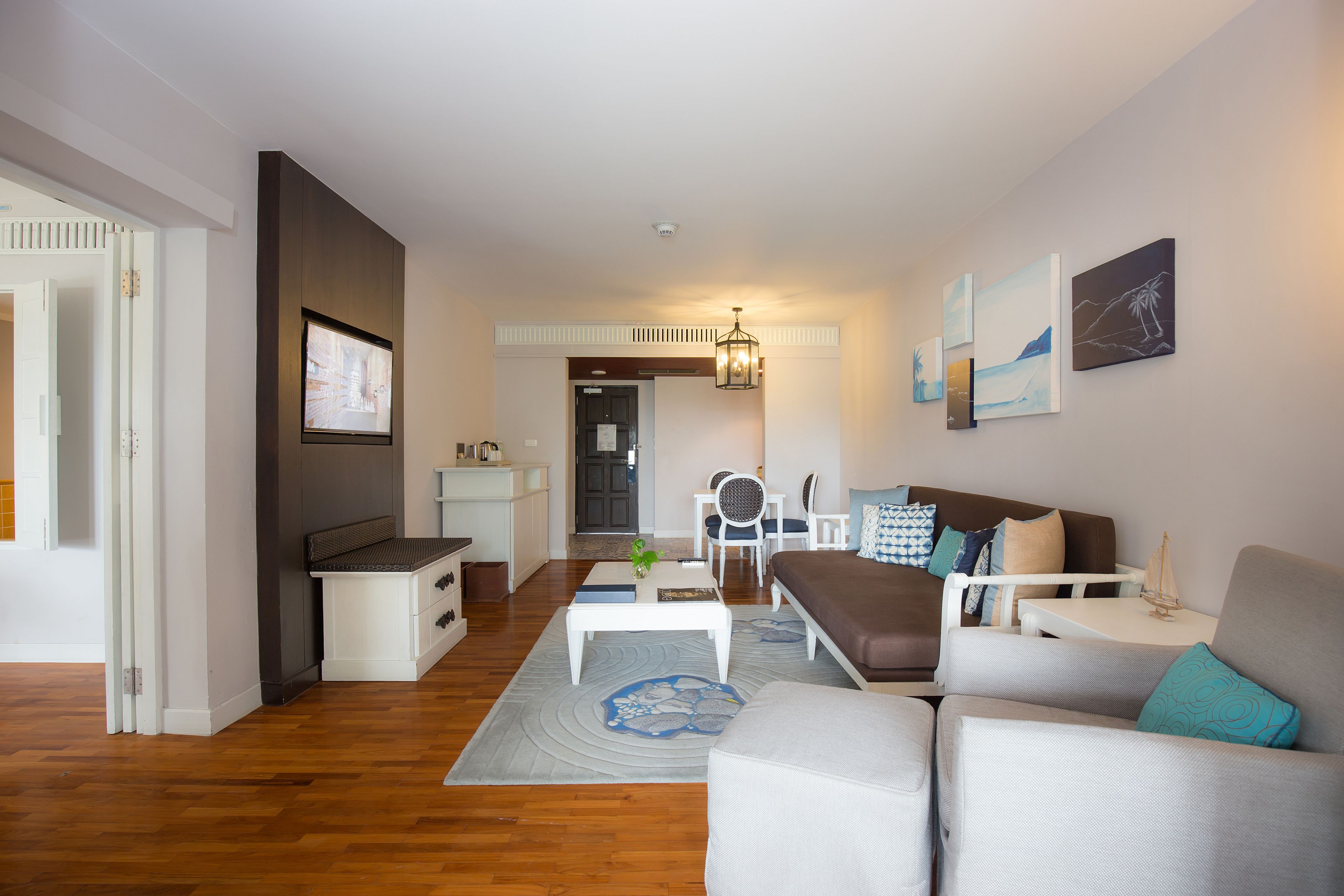 A modern living room with a sofa, armchairs, a coffee table, and artwork on the walls.