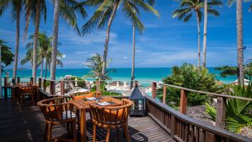 A wooden deck with outdoor seating and a view of the ocean.