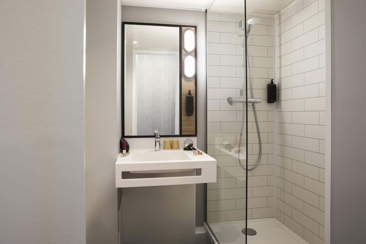 Une salle de bain moderne avec une douche à parois de verre, un lavabo blanc et un miroir.