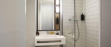 Un baño moderno con ducha de vidrio, lavamanos blanco y espejo.