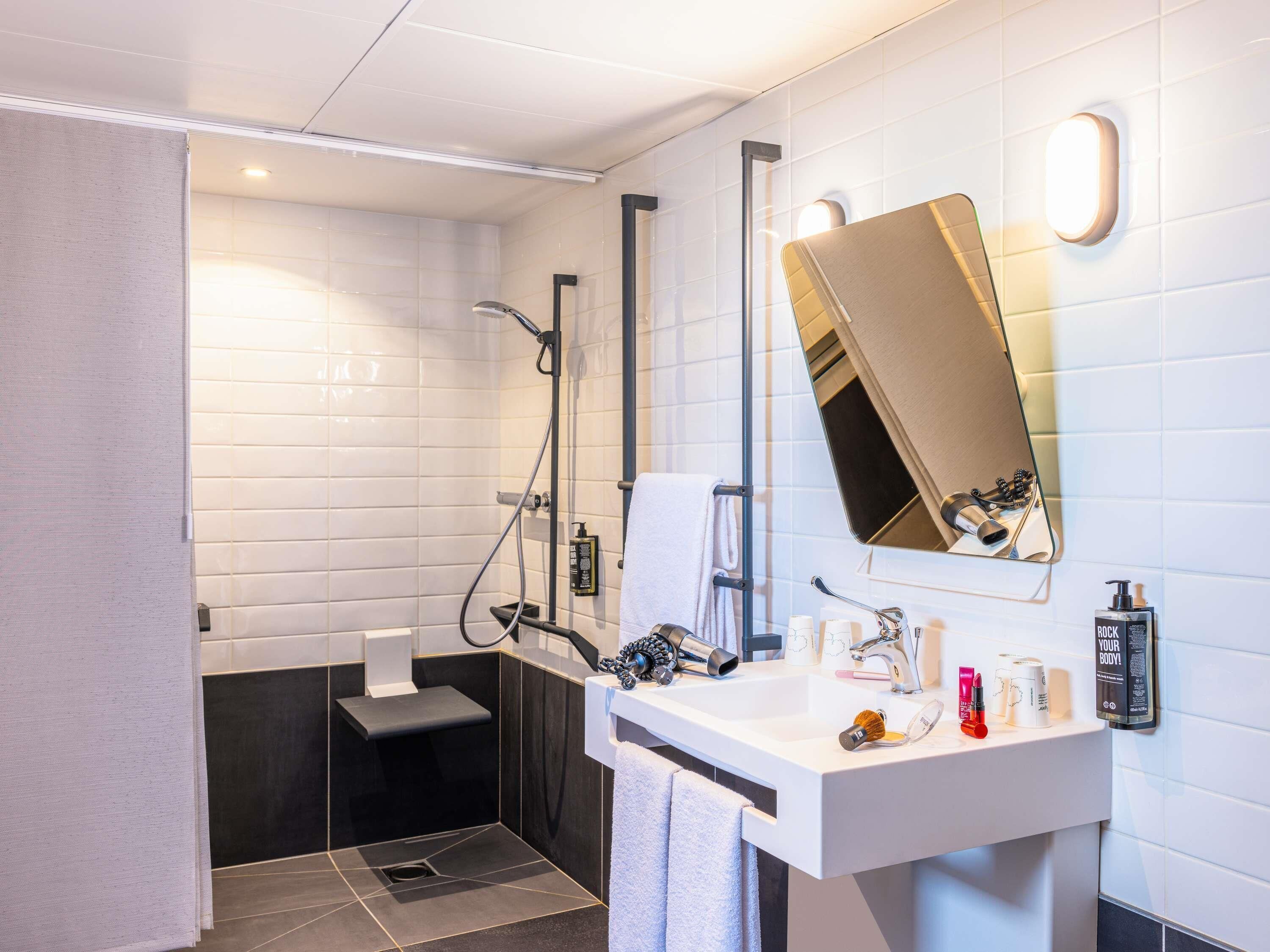 Ein modernes Badezimmer mit Dusche, Waschbecken und Pflegeprodukten sowie einem Spiegel.