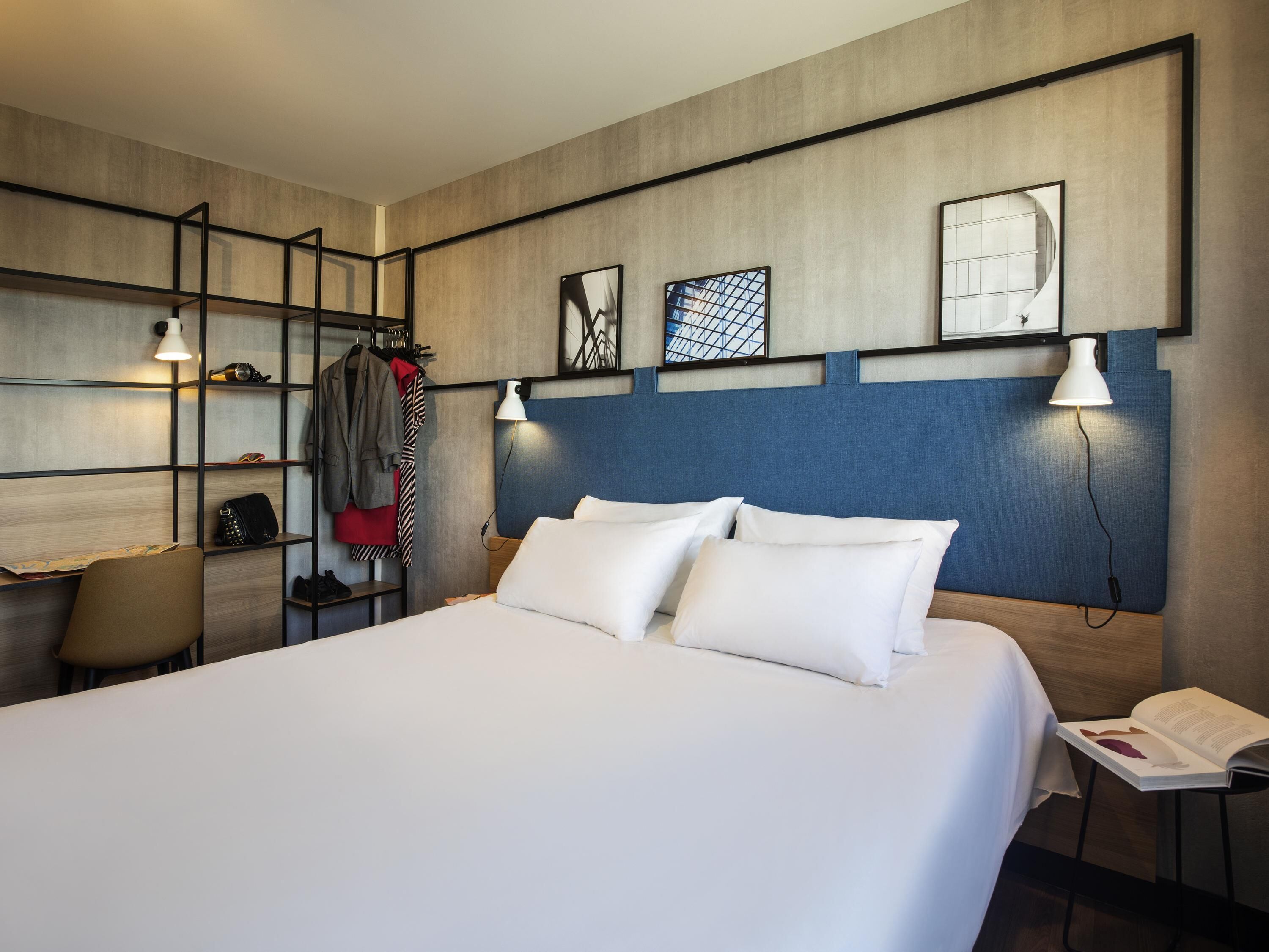 Una habitación de hotel moderna con una cama grande, un escritorio y un armario.