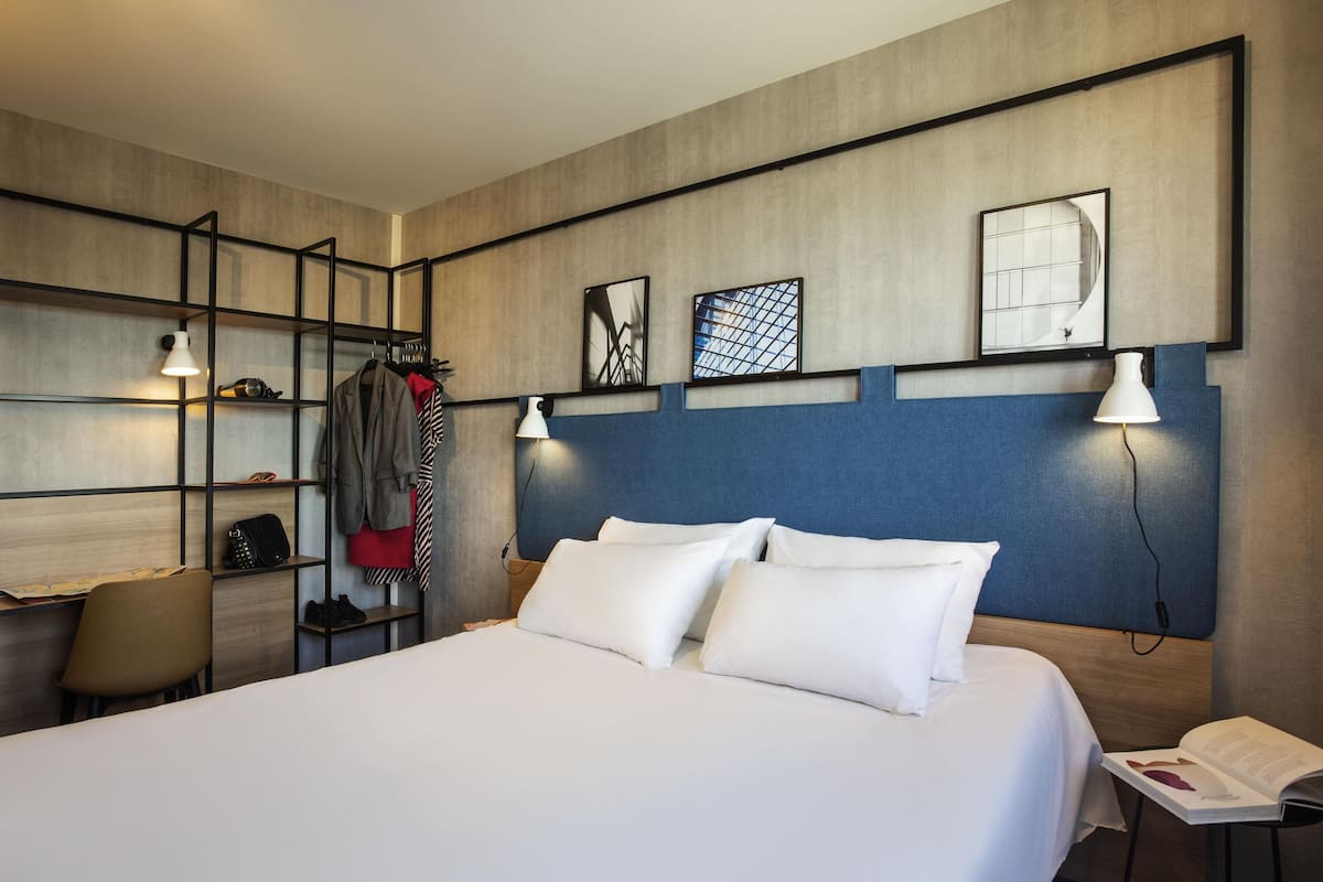 Ein modernes Hotelzimmer mit einem großen Bett, einem Schreibtisch und einem Kleiderschrank.