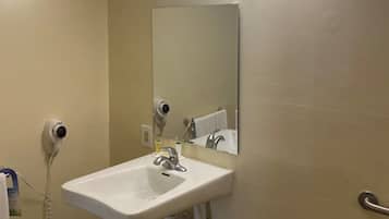 A bathroom with a white sink, a mirror, a towel rack, and a hairdryer on the wall.