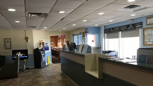 Zona de recepción con mostrador, televisor y quiosco de autoservicio.