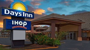 Señal de restaurante IHOP de Days Inn con logotipo de sol, una entrada cubierta y un edificio con techo de tejas.