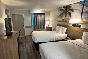 A hotel room with two beds, a desk, a TV, and a beach-themed wall mural. - Days Inn by Wyndham St. Augustine I-95/Outlet Mall (St. Augustine)