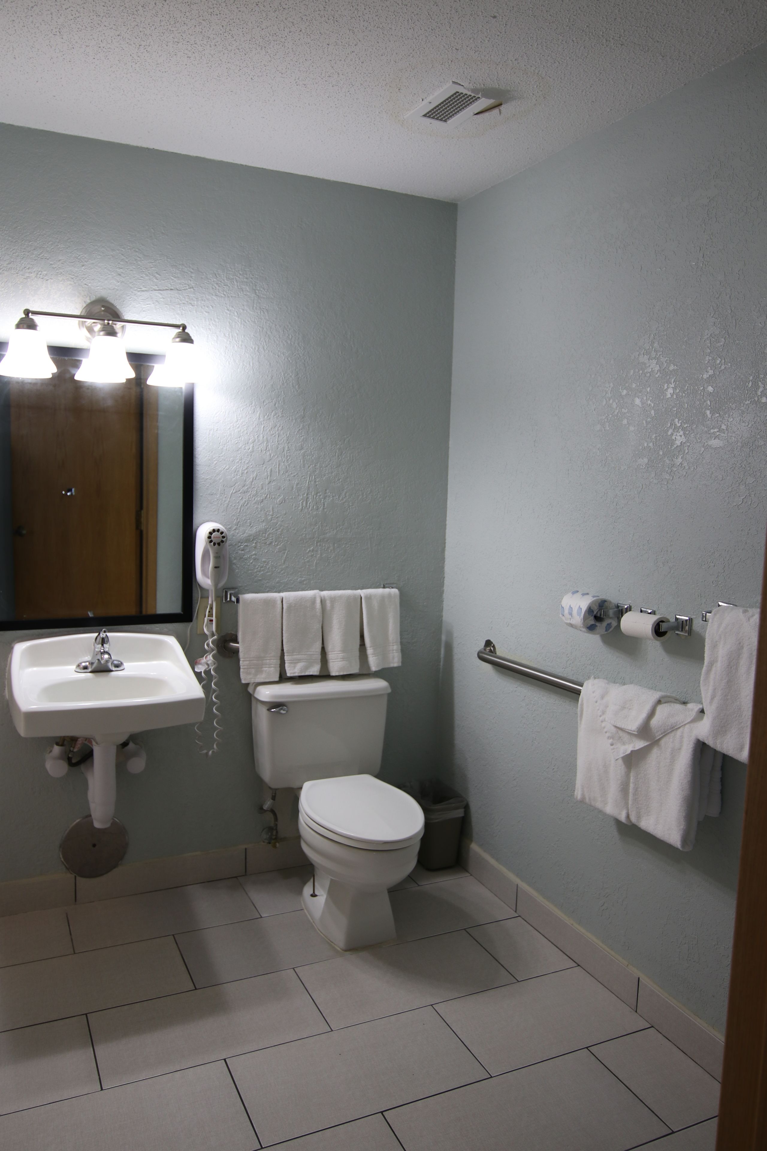 A bathroom with a sink, toilet, and towel rack.