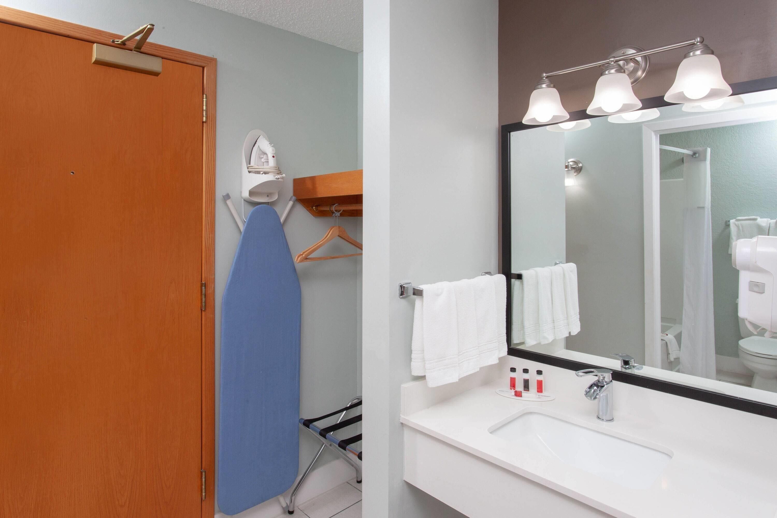 A bathroom with a wooden door, a blue towel, a white sink with a mirror, and a towel rack.