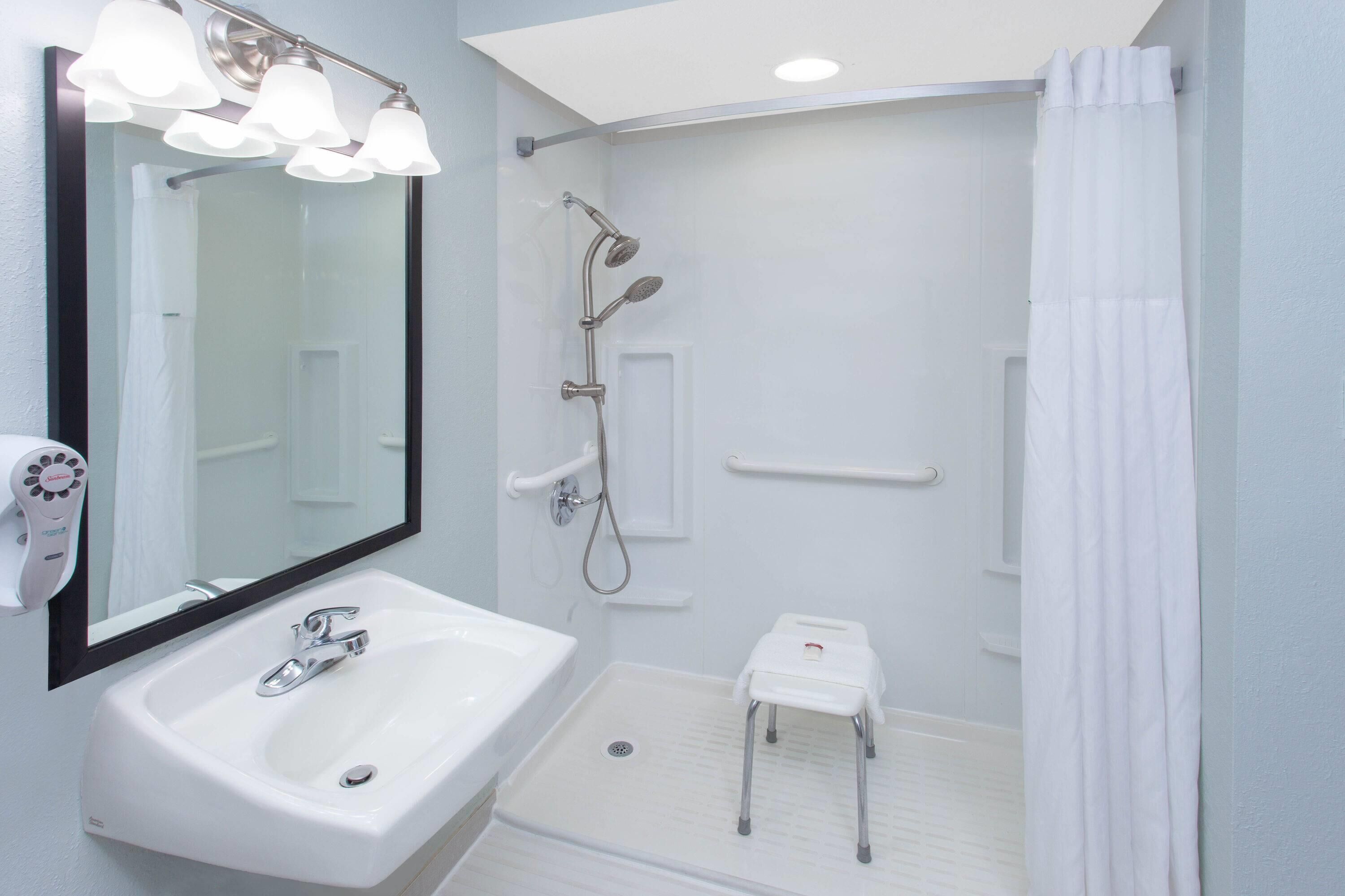 Een badkamer met een witte wastafel, spiegel en douche.