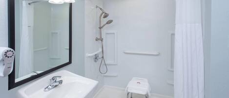 Een badkamer met een witte wastafel, spiegel en douche.