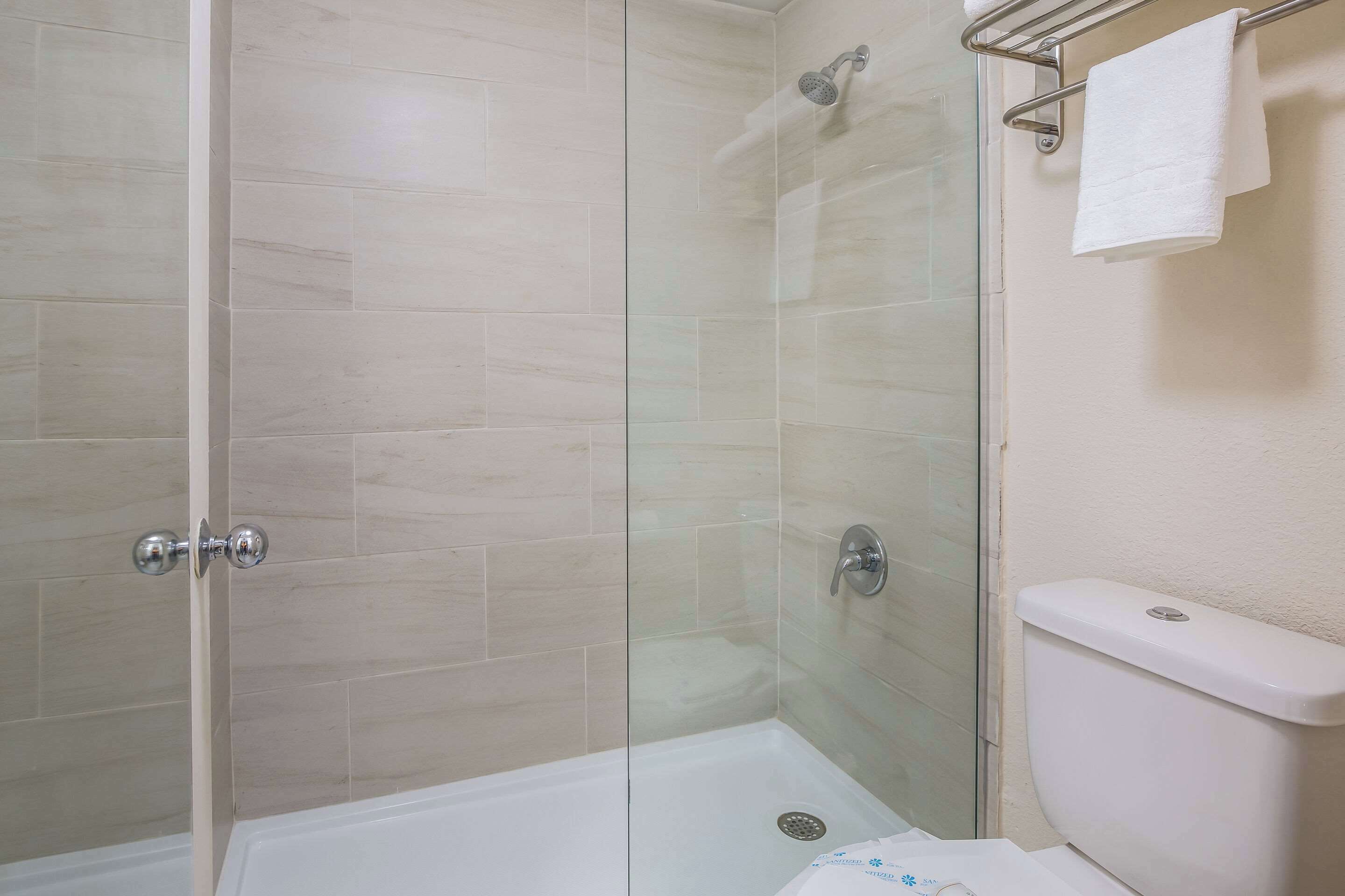 A shower with a glass door, a white bathtub, and a toilet.