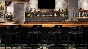 Un bar con pared de ladrillo, un tiburón montado en la pared y varias botellas y vasos en estanterías.