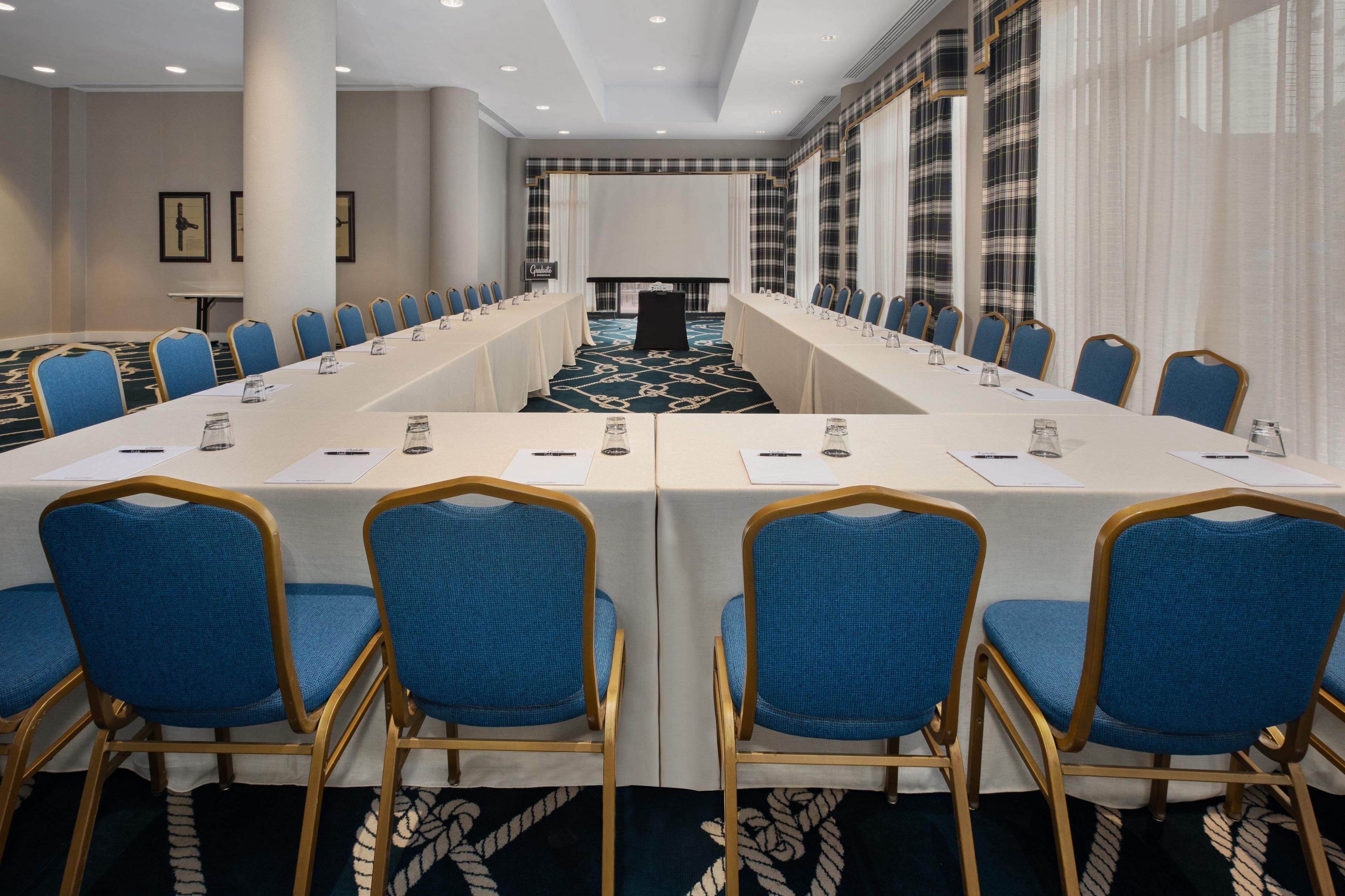 A conference room with a long table, blue chairs, and a carpeted floor.