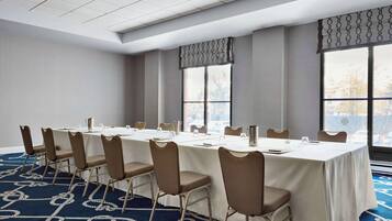 A conference room with a long table, chairs, and large windows.