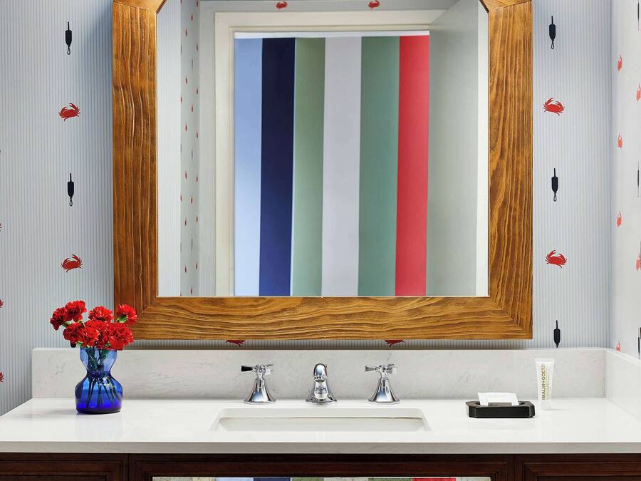 Un meuble-lavabo de salle de bain avec un miroir, des luminaires et un vase de fleurs.