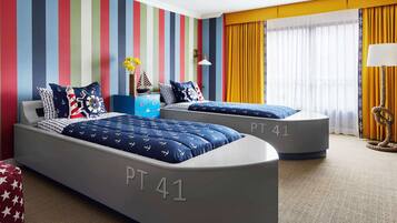 A hotel room with two beds labeled PT 41, striped walls, a small desk, and a window with curtains.